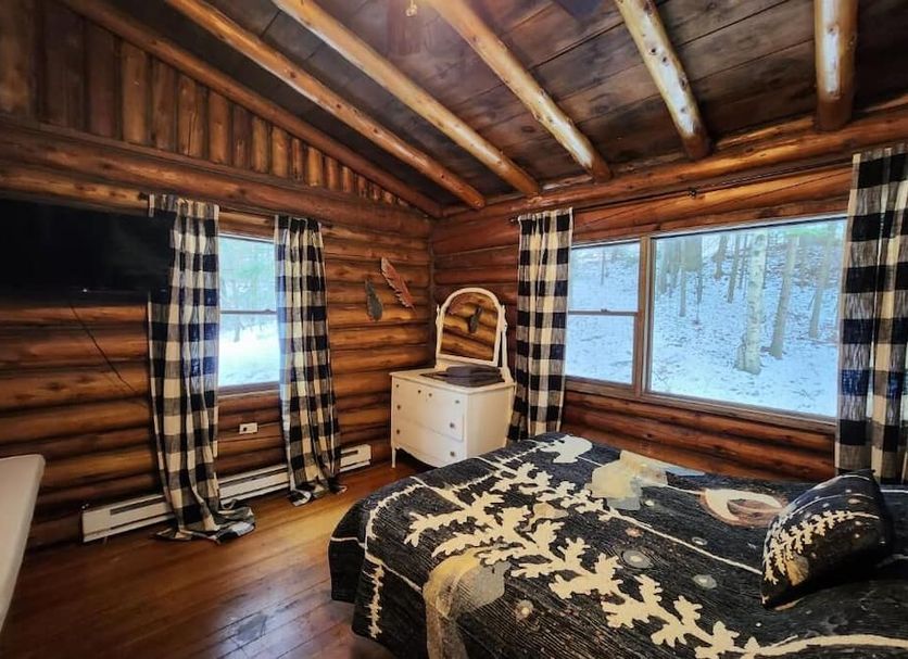 Adirondack Diamond Point Lodge in Lake George cabin-style room with log walls, wood ceiling, and forest-view windows