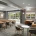 Homewood Suites by Hilton Alexandria/Pentagon South lobby lounge with tables, chairs and patio doors