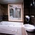 Çetinel Otel in Adana bathroom with jetted tub, wall-mounted sink, and dark tile walls