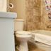 The Medicine Hat Villa bathroom with toilet, bathtub, towel, and tiled shower surround in Medicine Hat
