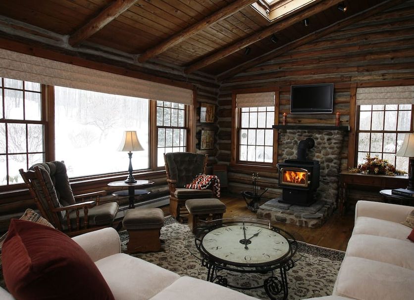 Chalet of Canandaigua lounge with stone fireplace, wood ceiling, large windows and rustic seating