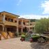Residence Corte Dei Venti in Budoni with Mediterranean-style buildings, stairs, courtyard, and tree-lined garden