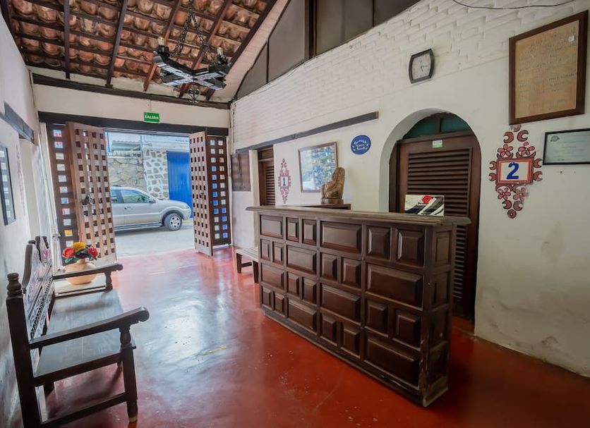 Hotel Mision Y Spa Acapulco lobby with wooden front desk, bench seating, and open entrance