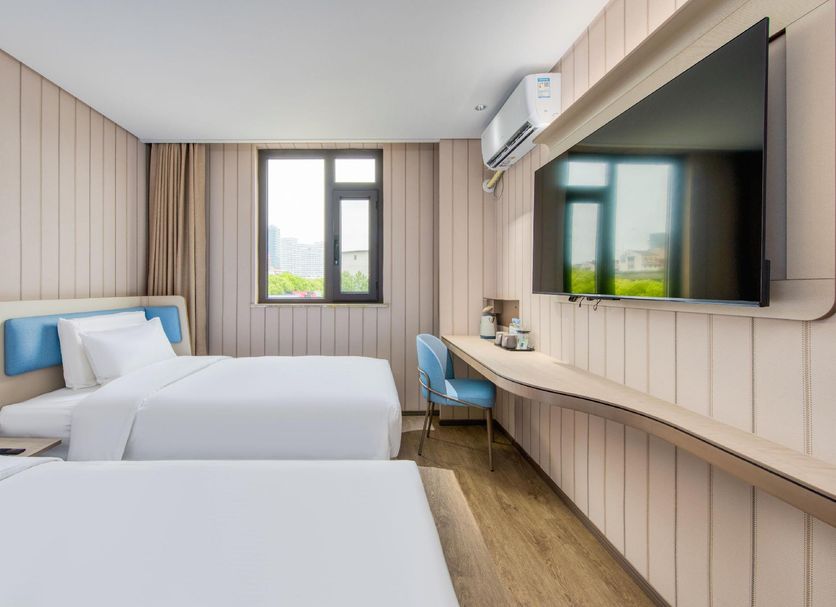 Hanting Hotel Wuxi Railway Station Guangrui Road room with two beds, desk, wall TV and window