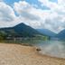 Karma Bavaria in Schliersee with lakefront view, pebbled shore, mountains and cloudy sky