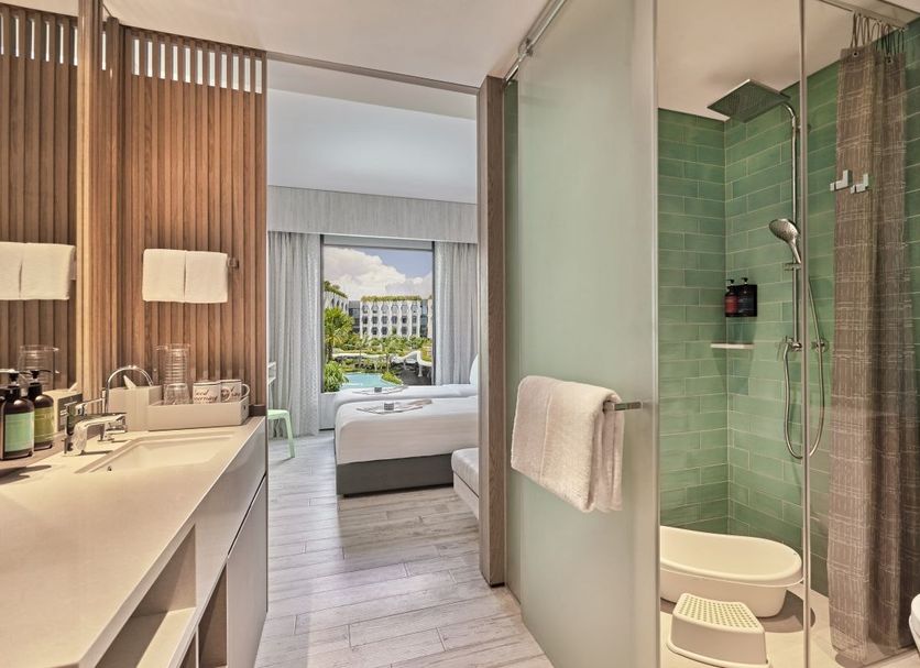Village Hotel Sentosa by Far East Hospitality bathroom with green-tile shower and bedroom view to balcony, Singapore