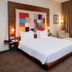 The Landmark Hotel Baku guest room with king bed, colorful wall art, armchair and city-view window