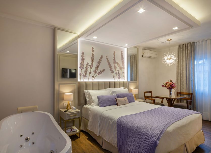 Blumen Hotel Boutique in Canela room with a bed, lounge chairs, and a freestanding bathtub
