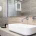 Hotel Roumani in Spétses bathroom with glass shower, wall-mounted sink, and wood-look tile