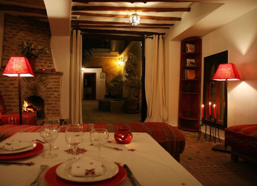 Riad Dar Nimbus in Marrakech room with table setting, fireplace, red lamps, and courtyard view