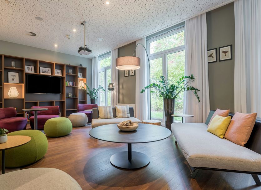 Citadines Arnulfpark Munich lounge in Munich with colorful seating, large windows, and a central coffee table
