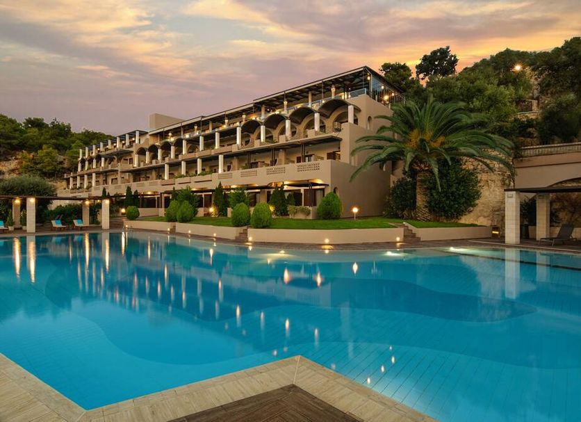 Royal Sun Hotel in Chania with a large outdoor pool and hillside hotel building at sunset