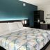 Studio 6 Suites Lafayette room with king bed, teal accent wall, microwave and mini-fridge