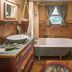 Country Woods Inn Glen Rose rustic bathroom with clawfoot tub, wood paneling, patterned curtains and vanity