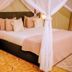 Heritage By Serendib in Blantyre features a canopy bed with white drapes and bedside lamp