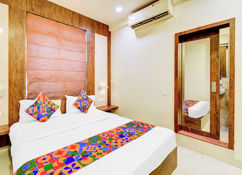 Fabhotel Arastu Plaza Hyderabad room with double bed, colorful runner, wall mirror and air conditioner