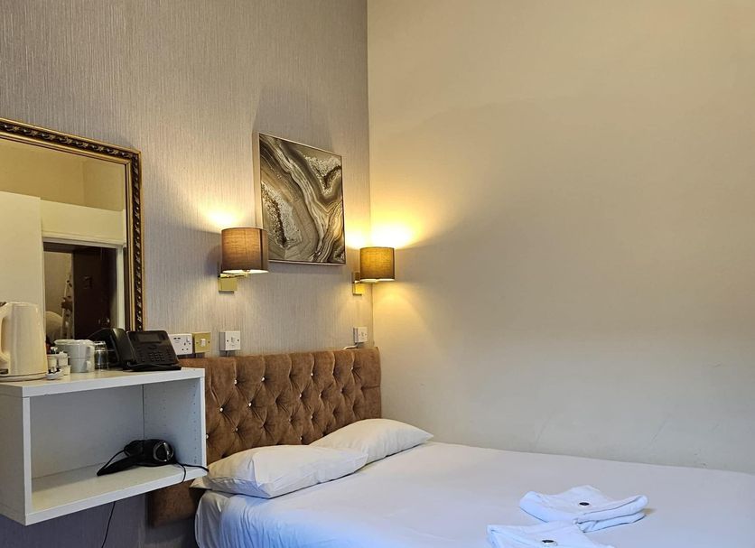 Hyde Park Court Hotel London guest room with single bed, wall lamps, and a small shelf