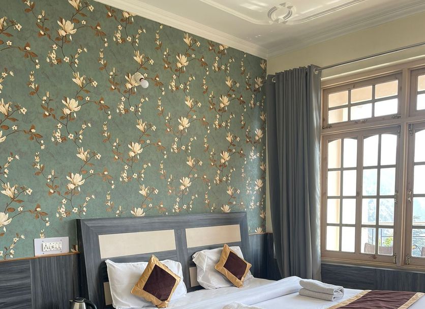 Hotel Sky Pie room in Dharamshala with floral wallpaper, king bed, sofa and large window