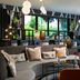 Leonardo Hotel Vienna Hauptbahnhof lounge with curved gray sofa, orange chairs, round tables and hanging globe lights