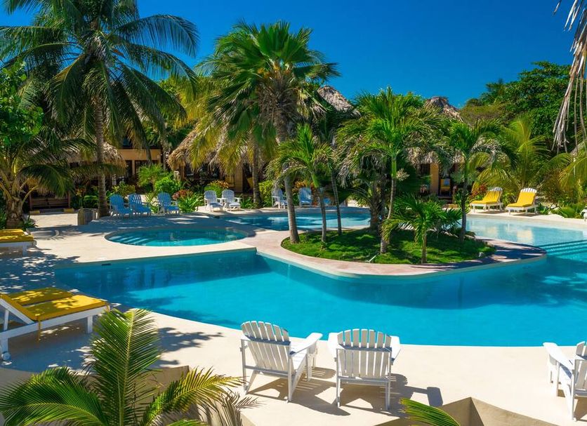 Portofino Beach Resort in San Pedro Town with a tropical lagoon-style pool and palm trees