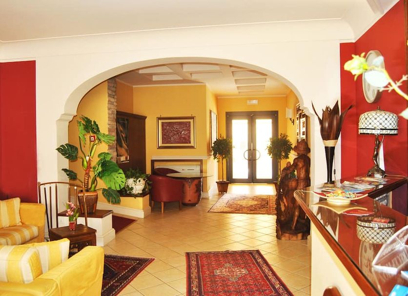 Greta Rooms Hotel in Mazara del Vallo lobby with red walls, archway, tiled floor, and plants