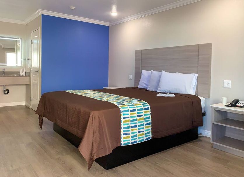 Mojave Inn Victorville guest room with king bed, blue accent wall, and small bedside table
