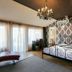 Vila Vidalis in Cluj Napoca: guest room with wrought-iron bed, chandelier, and large window curtains