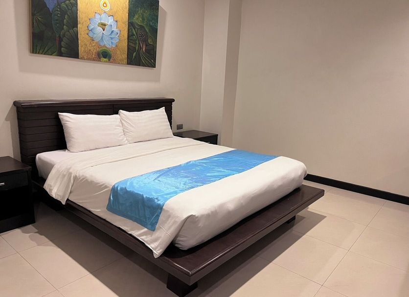 Lub Sbuy Hostel in Phuket City guest room with bed, white linens and blue runner
