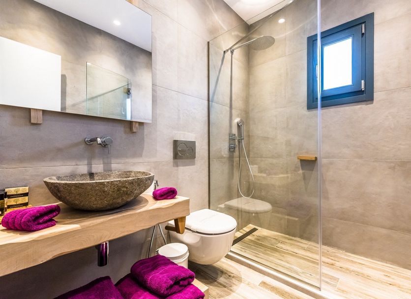 Portes Suites & Villas Mykonos bathroom with walk-in shower, stone sink, and toilet in Mykonos