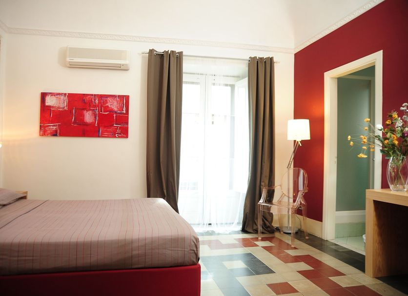 Sangiuliano114 B&B in Catania guest room with bed, balcony doors, floor lamp, and red accent wall