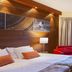 Lapland Hotels Riekonlinna Saariselka guest room with bed, red sofa and forest-view window