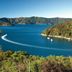 Bay of Many Coves, Picton: scenic bay view with blue water, forested hills, and boats leaving wakes
