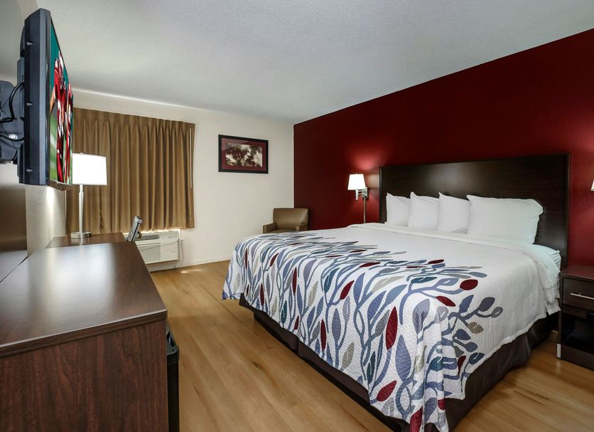 Red Roof Inn Hillsville guest room with king bed, red accent wall, TV and window with curtains