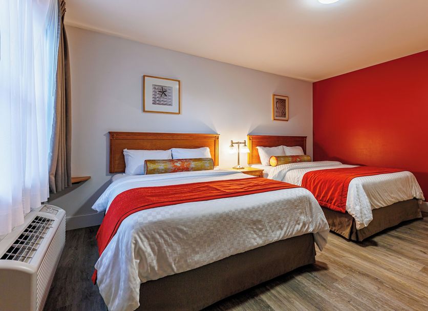 Hôtel-Motel Castel de la Mer in La Malbaie: guest room with two beds, red accent wall, and window