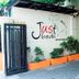 Justbeds Bangkok exterior with gated entrance, potted plants, and wall logo