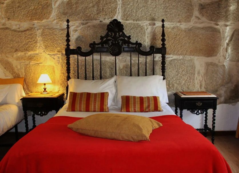 Alvares Cabral Guest House in Porto, stone-walled guest room with ornate iron bed and red bedspread