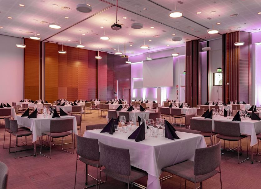 Holiday Club Vierumäki banquet hall with set dining tables and pink-purple lighting in Vierumäki