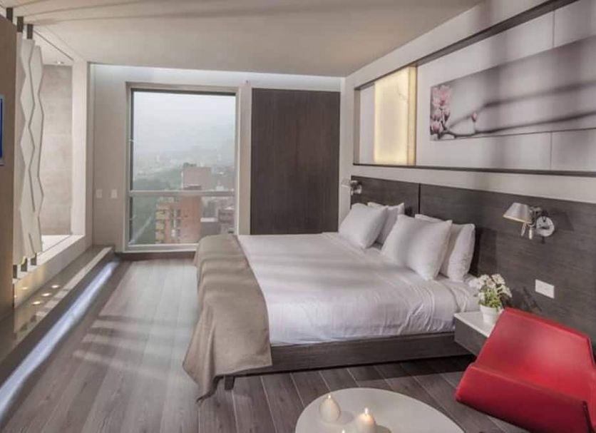 Inntu Hotel Medellín guest room with king bed, floor-to-ceiling window and city view