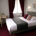 Hotel Le Canada in Hermanville-sur-Mer guest room with double bed, desk, red curtains and wall sconces