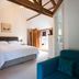 The Old Dairy at Bishops Barton in Wellington, bedroom with exposed beams and teal chair