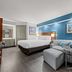 Baymont by Wyndham Tuscaloosa guest room with king bed, blue accent wall, and curved sofa seating