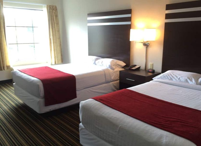 The Inn Monaca guest room with two double beds, window light, and bedside lamp