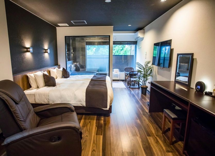 Livemax Resort Hakone Ashinoko room with king bed, recliner, desk and balcony view in Hakone