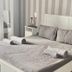 Enna Inn Centro in Enna: white bed with gray bedding, striped wallpaper, and bedside tables