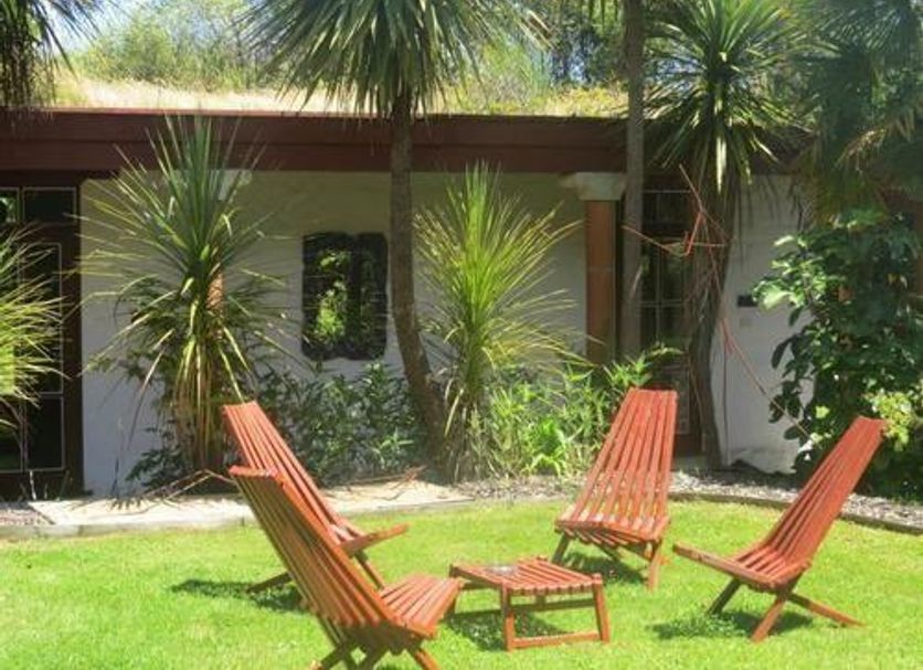 Sans Souci Inn, Pohara: outdoor garden seating with wooden chairs and small table beneath palm trees