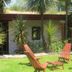Sans Souci Inn, Pohara: outdoor garden seating with wooden chairs and small table beneath palm trees