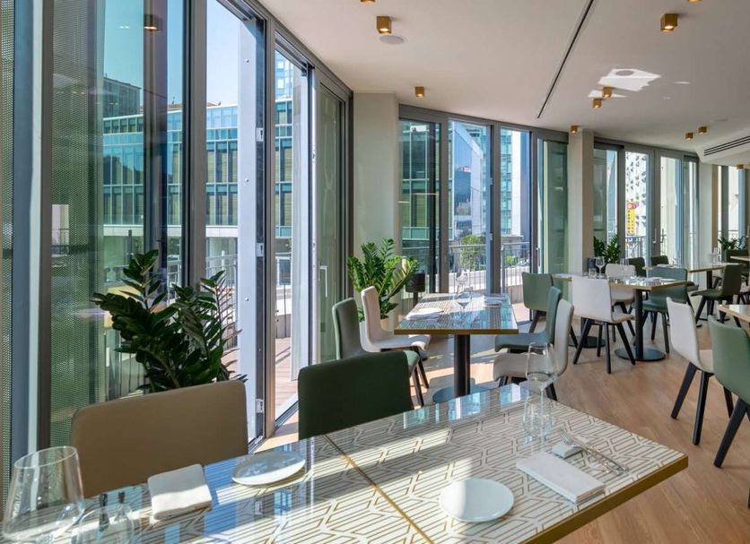Hotel Tocq Milan dining area with floor-to-ceiling windows and city views