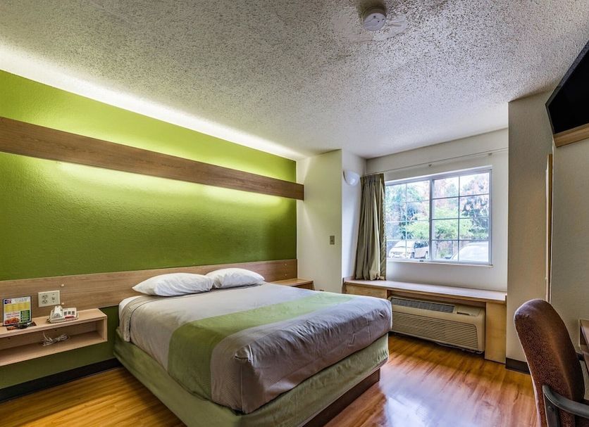 Motel 6 Charlotte University guest room with bed, window seat, and wall-mounted TV in Charlotte