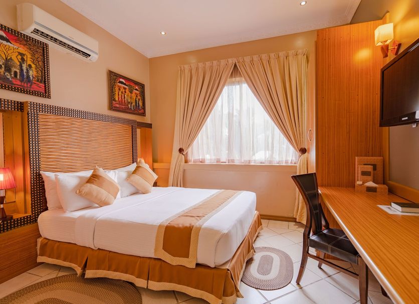 The Amariah Boutique Hotel Mikocheni room with bed, desk, wall TV and window in Dar Es Salaam