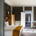 B&B The Verhaegen Ghent guest room with bed, desk, tall windows and mustard curtains